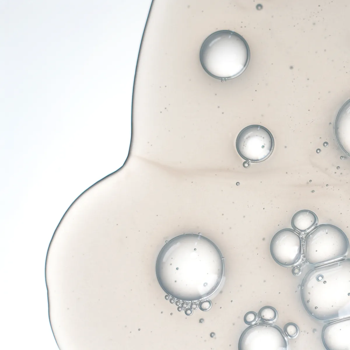 Transparente Shampoo-Textur mit feinen und großen Bläschen in einer Makroaufnahme.