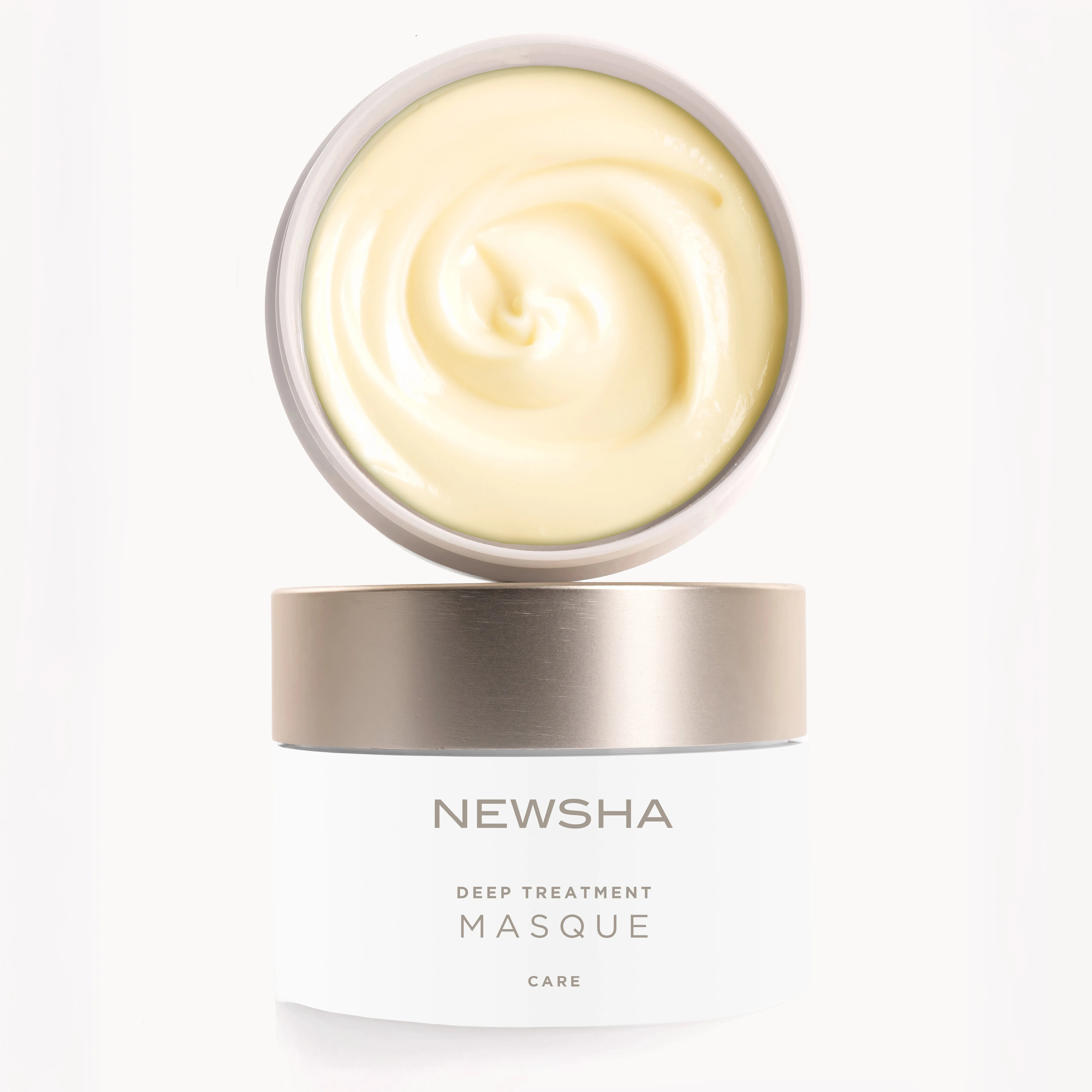 Geöffnete NEWSHA Deep Treatment Masque mit cremiger Textur und goldenem Deckel vor hellem Hintergrund.