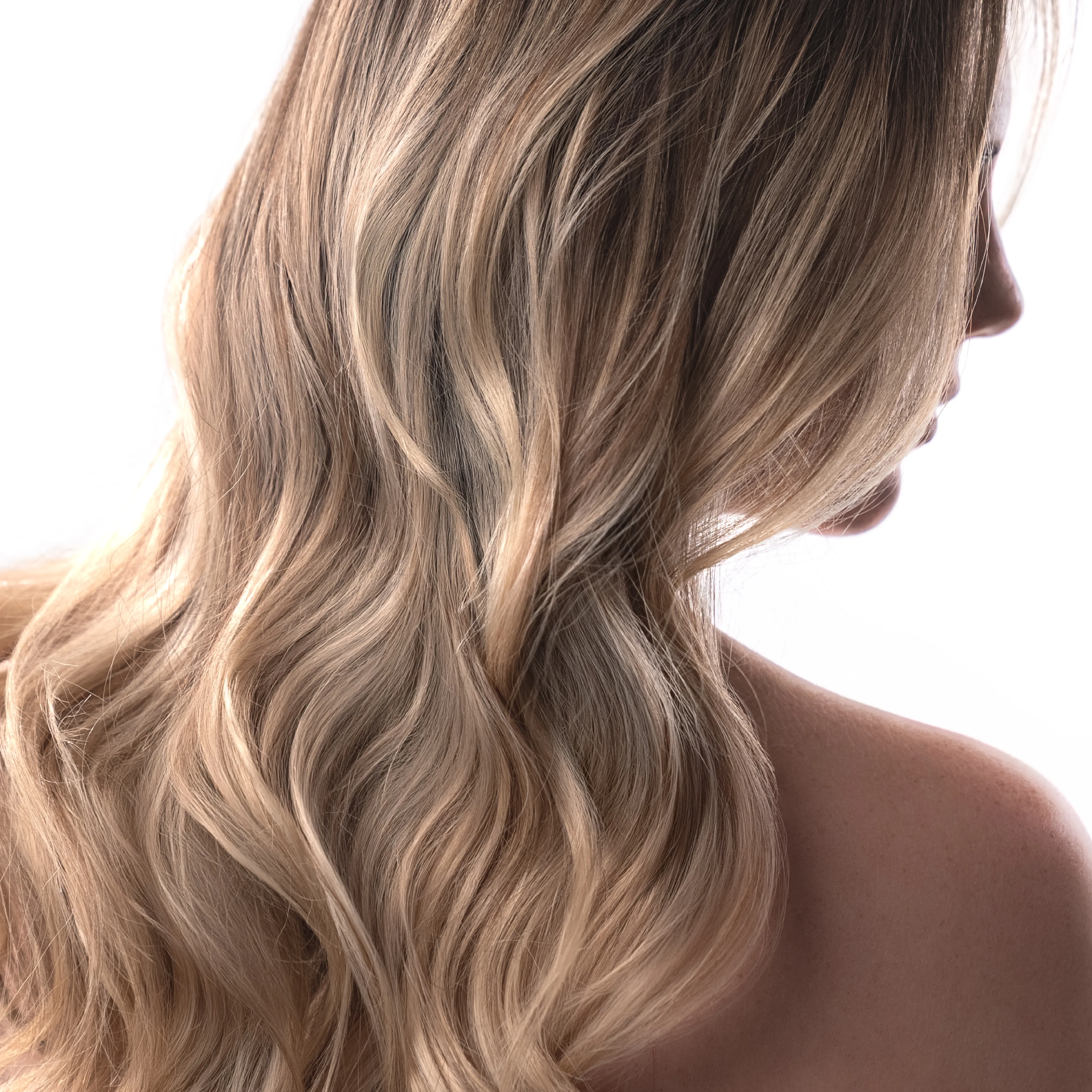 Lange blonde Haarwellen mit nat&uuml;rlichem Farbverlauf und gl&auml;nzendem Finish in R&uuml;ckenansicht.