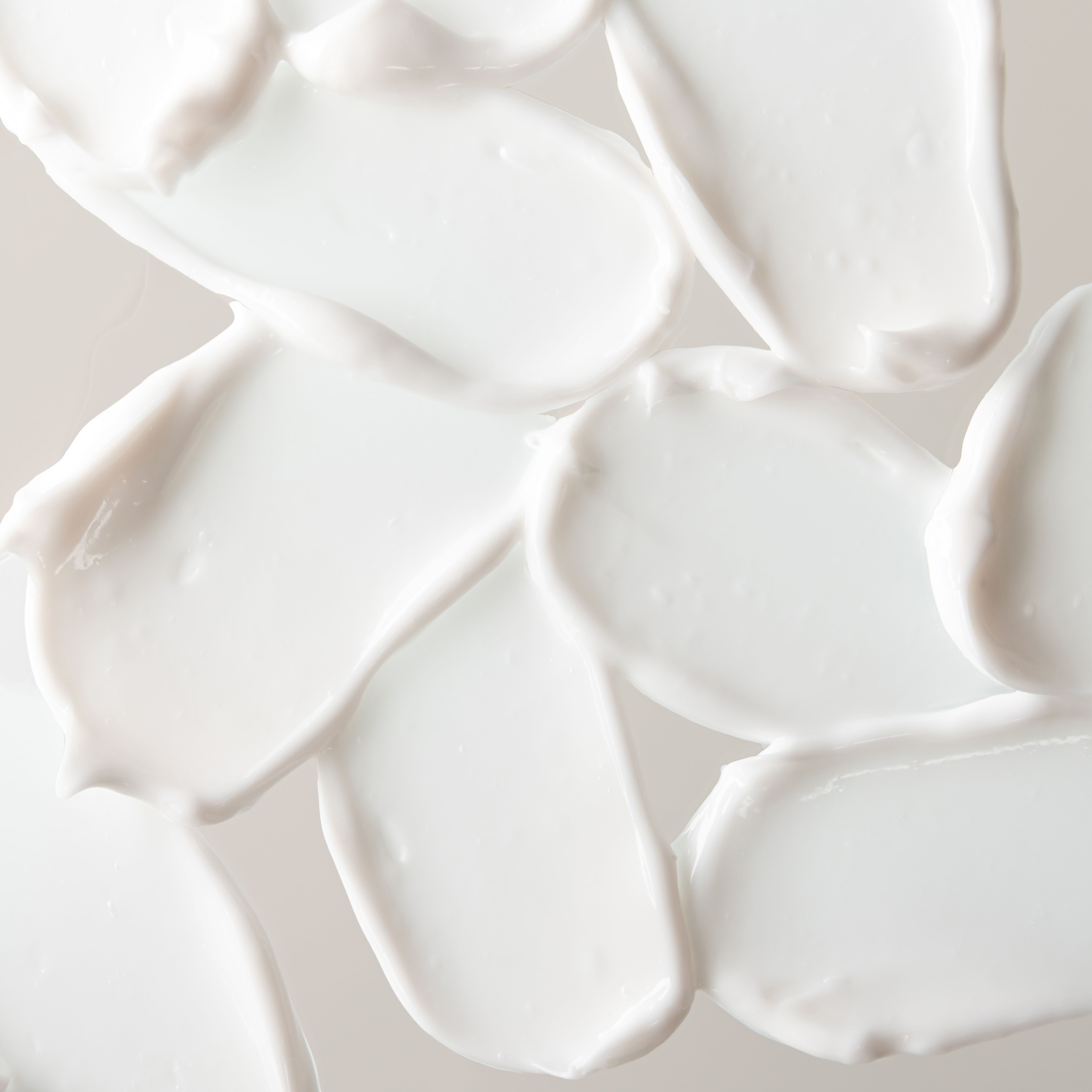 Reichhaltige weiße Creme-Textur mit geschmeidiger Konsistenz und sanften Lichtreflexen auf hellem Untergrund.