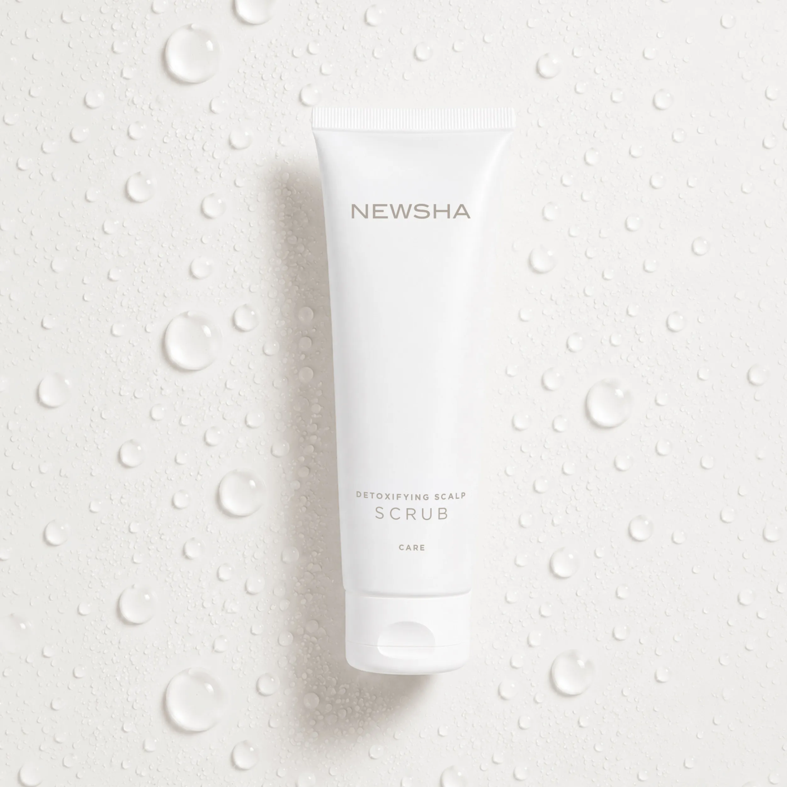 NEWSHA Detoxifying Scalp Scrub als freigestelltes Produktbild vor hellem Hintergrund mit feinen Wassertropfen.