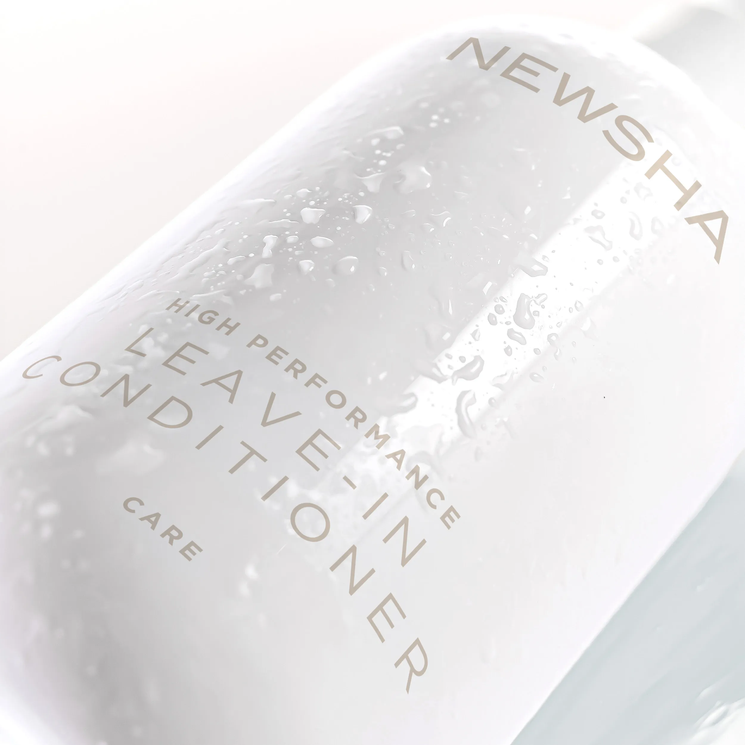 Detailaufnahme des NEWSHA High Performance Leave-In Conditioner mit feinen Wassertropfen auf der Verpackung vor hellem Hintergrund.