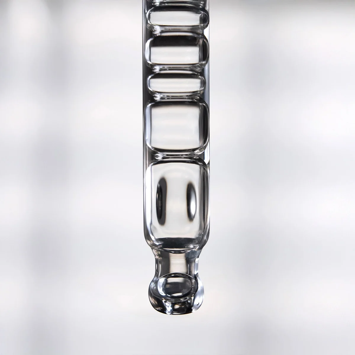 Makroaufnahme einer gl&auml;sernen Pipette mit transparenter Serumtextur und sichtbaren Luftkammern vor einem minimalistischen Hintergrund.