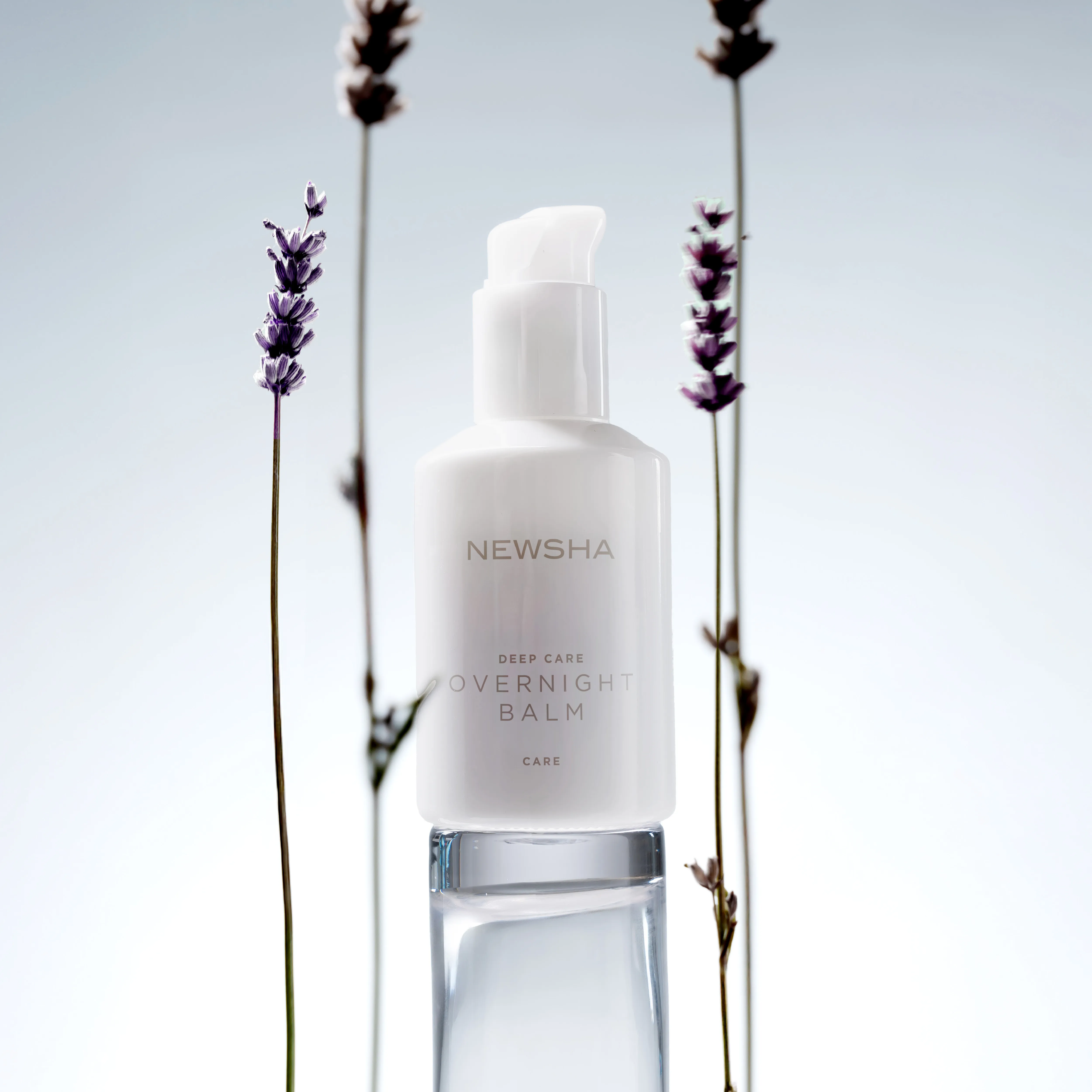 Der NEWSHA Deep Care Overnight Balm steht zwischen Lavendelzweigen und symbolisiert intensive Nachtpflege f&uuml;r geschmeidiges Haar.